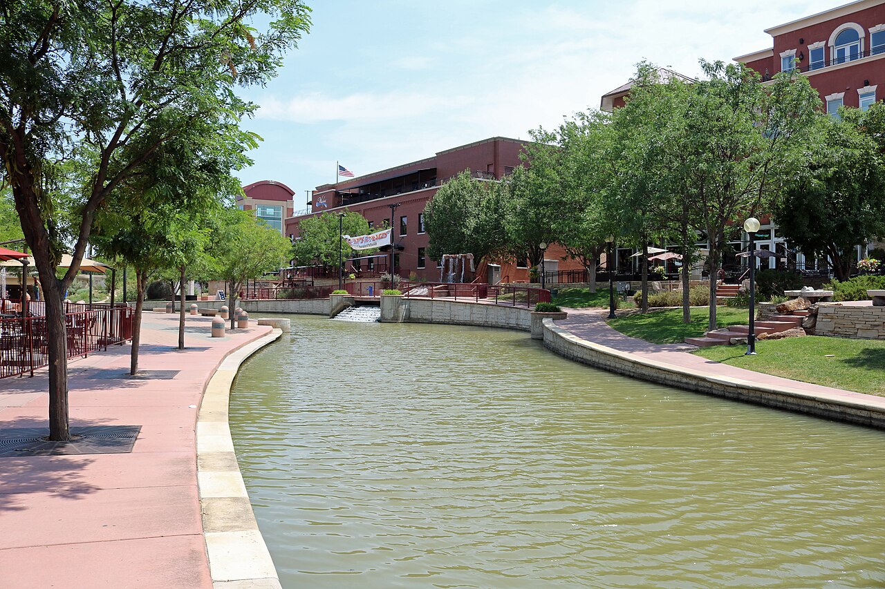 Boats drift past the riverwalk as festival crowds gather nearby